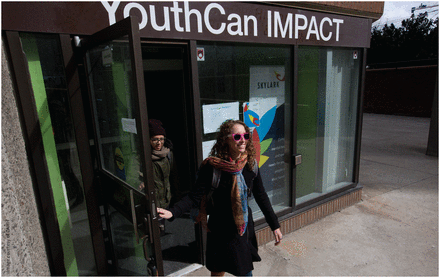 Photograph of a young woman, smiling, as she exits the YouthCAN Impact office.