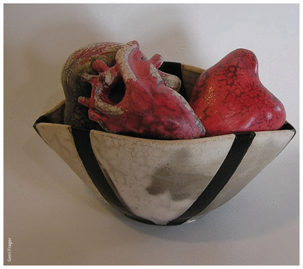Colour photo of an artwork: a white bowl with 2 black stripes holds 3 red human hearts, made of clay.