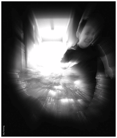 Photo of a young boy running down a corridor, smiling.